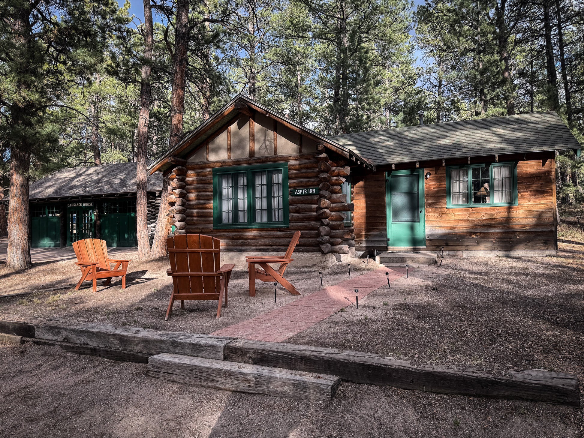 Wooden cabin in a forest setting with chairs and a fire pit at Creepaway Camp, La Foret Conference and Retreat Center, Black Forest, Colorado.