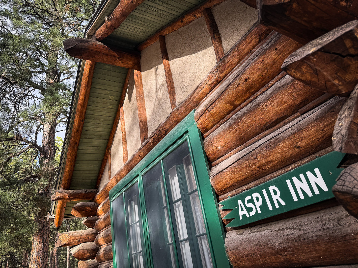 Log cabin with a sign reading 'Aspir Inn' in a forest setting at Creepaway Camp, La Foret Conference and Retreat Center, Black Forest, Colorado.