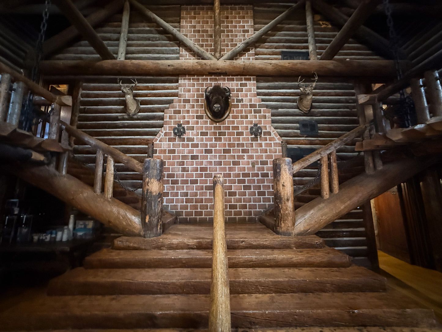 Wooden staircase leading to a brick fireplace with decorative elements in a rustic interior. Creepaway Camp, Ponderosa Lodge, La Foret Conference and Retreat Center, Black Forest, Colorado.