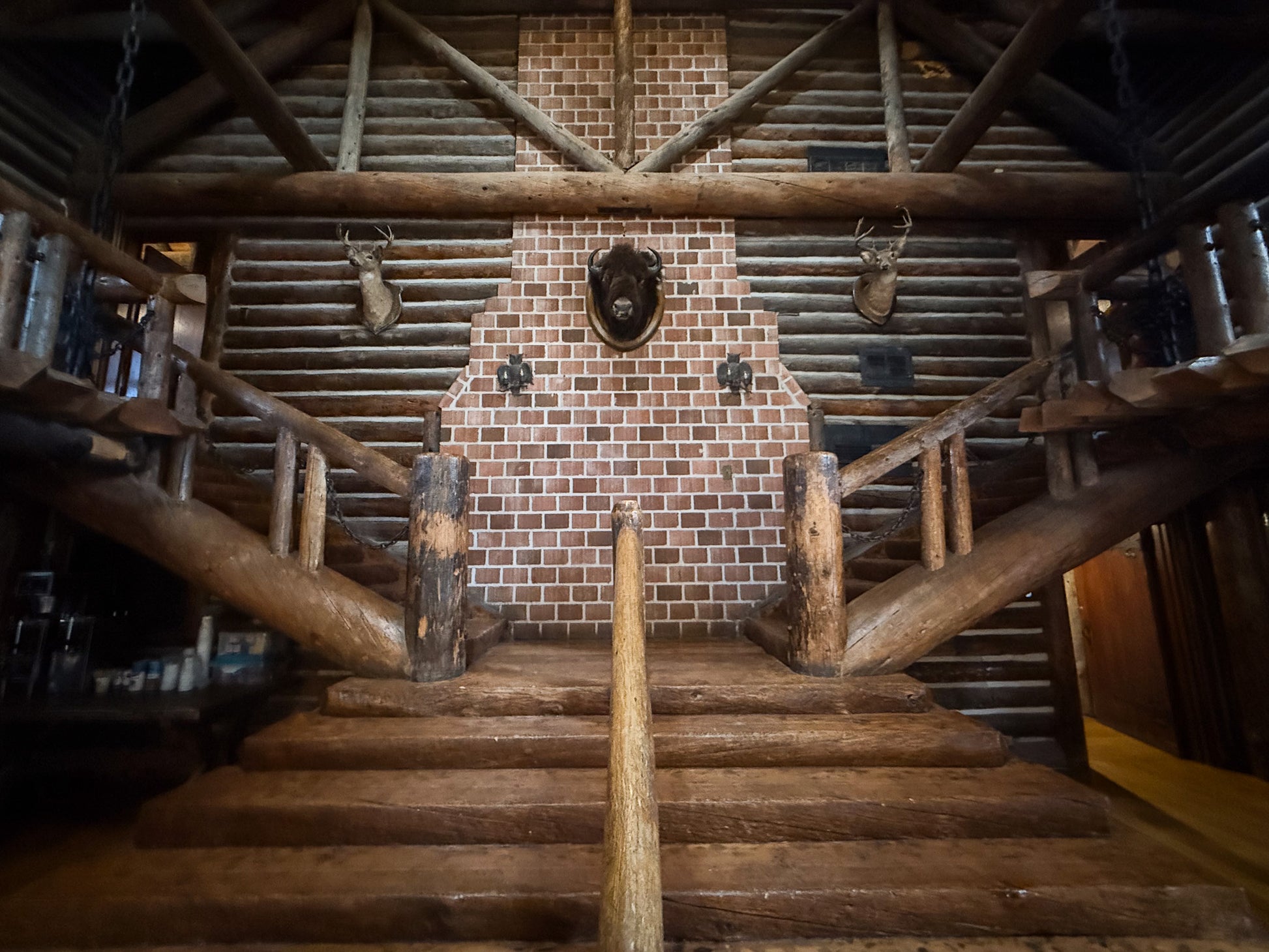 Wooden staircase leading to a brick fireplace with decorative elements in a rustic interior. Creepaway Camp, Ponderosa Lodge, La Foret Conference and Retreat Center, Black Forest, Colorado.