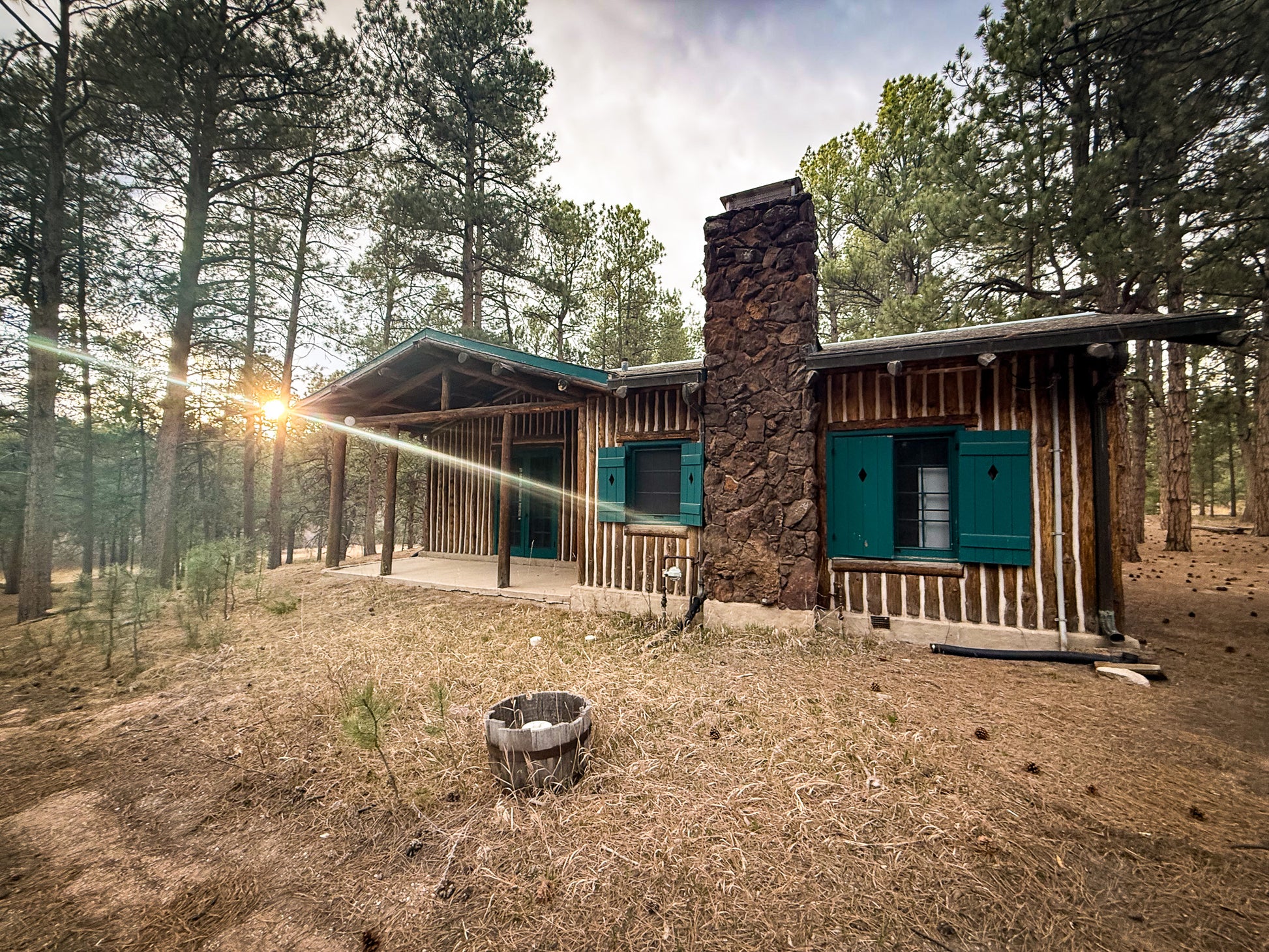 Wooden cabin in a forest with a fire pit in the foreground at Creepaway Camp, La Foret Conference and Retreat Center, Black Forest, Colorado.